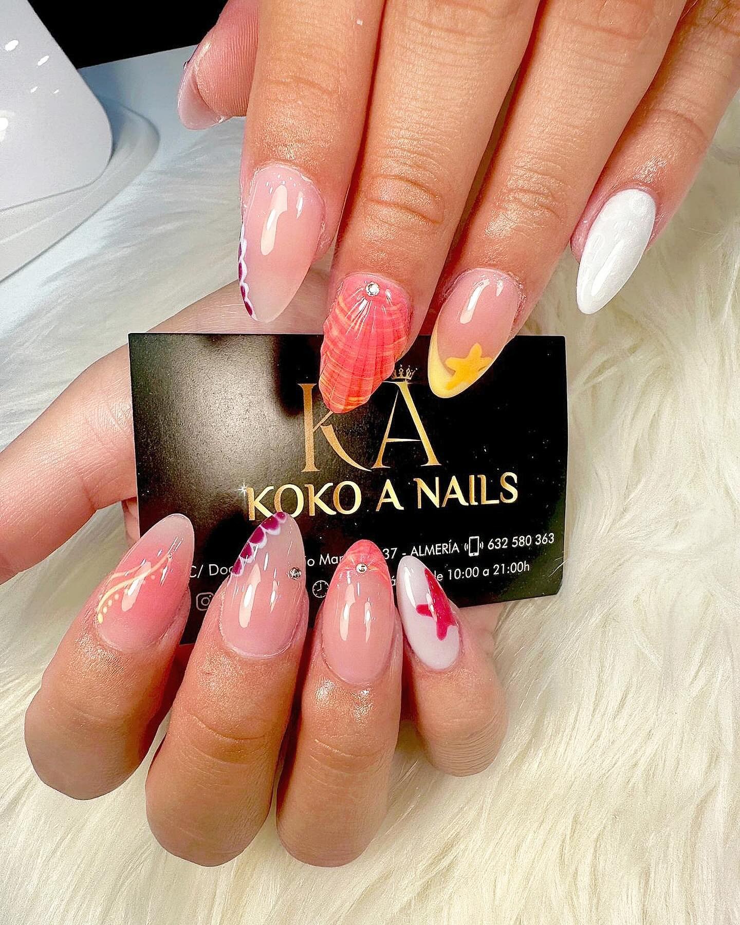 Uñas almendradas medianas en rosa, blanco y amarillo con flores, junto a la tarjeta del salón