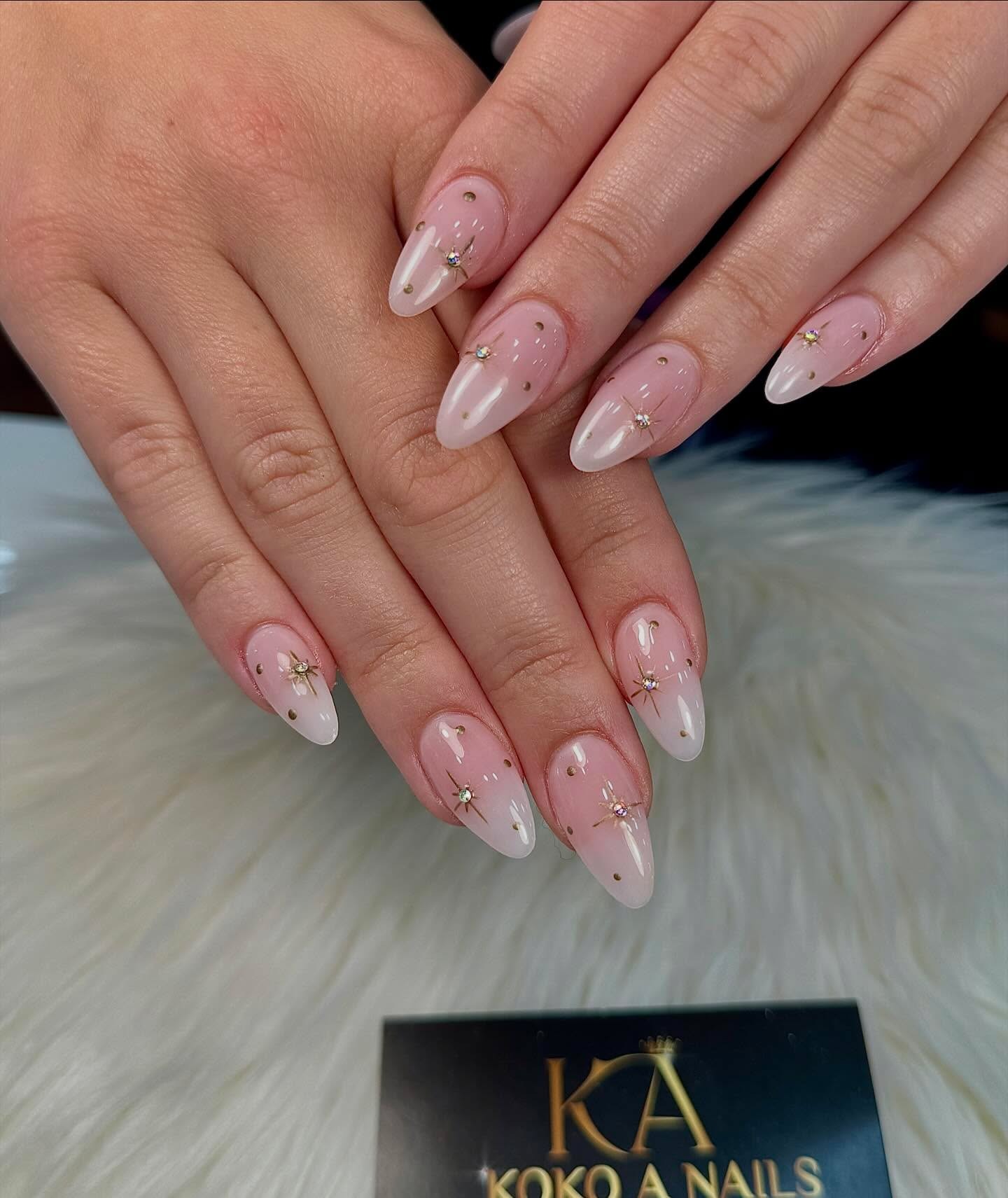 Uñas almendradas con degradado de rosa a blanco y finas cadenas doradas