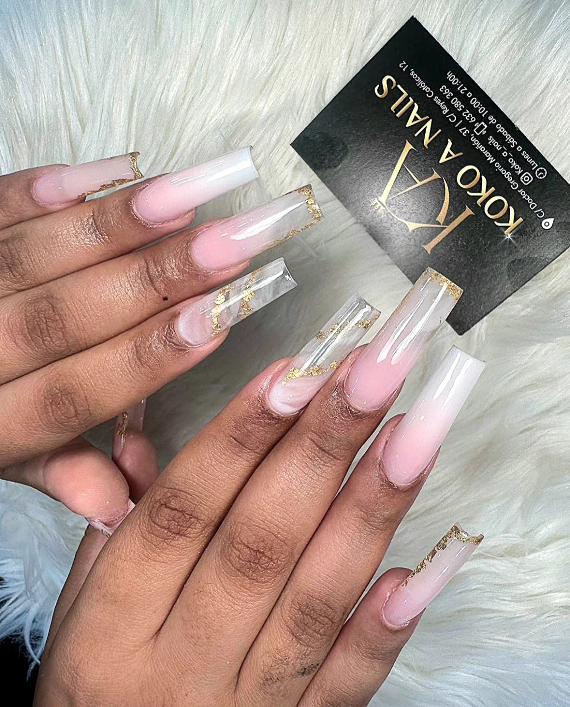Manos sobre pelo blanco con uñas coffin largas en degradado rosa y detalles dorados, tarjeta de Koko A Nails